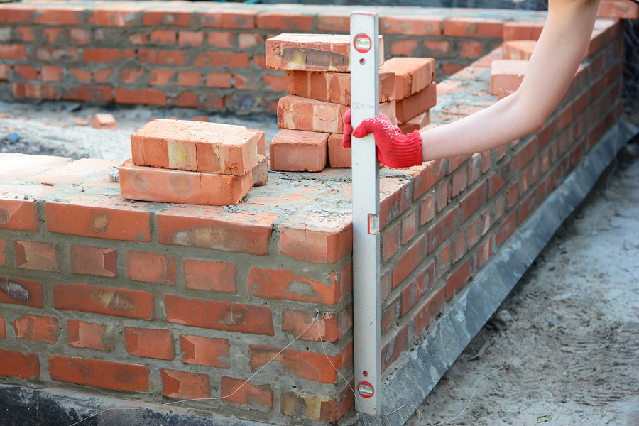 man measuring a brick wall